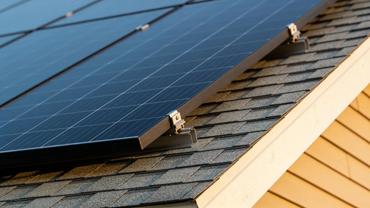 Panneaux solaires reflétant le soleil sur une toiture en tuiles sombres, dans le secteur de Figeac